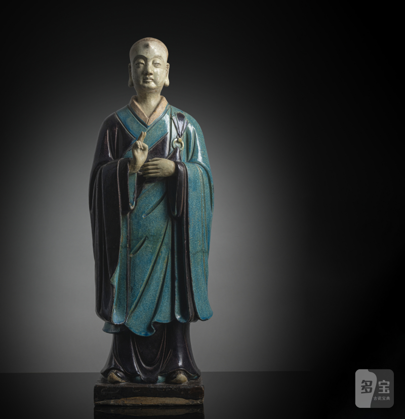 A large pottery figure of a standing Luohan with tricolour glaze, right hand raised